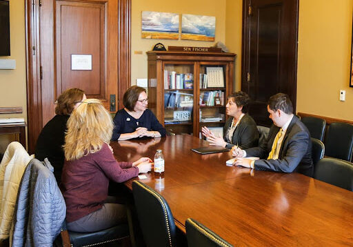 5 people seated around a conference table in discussion. 