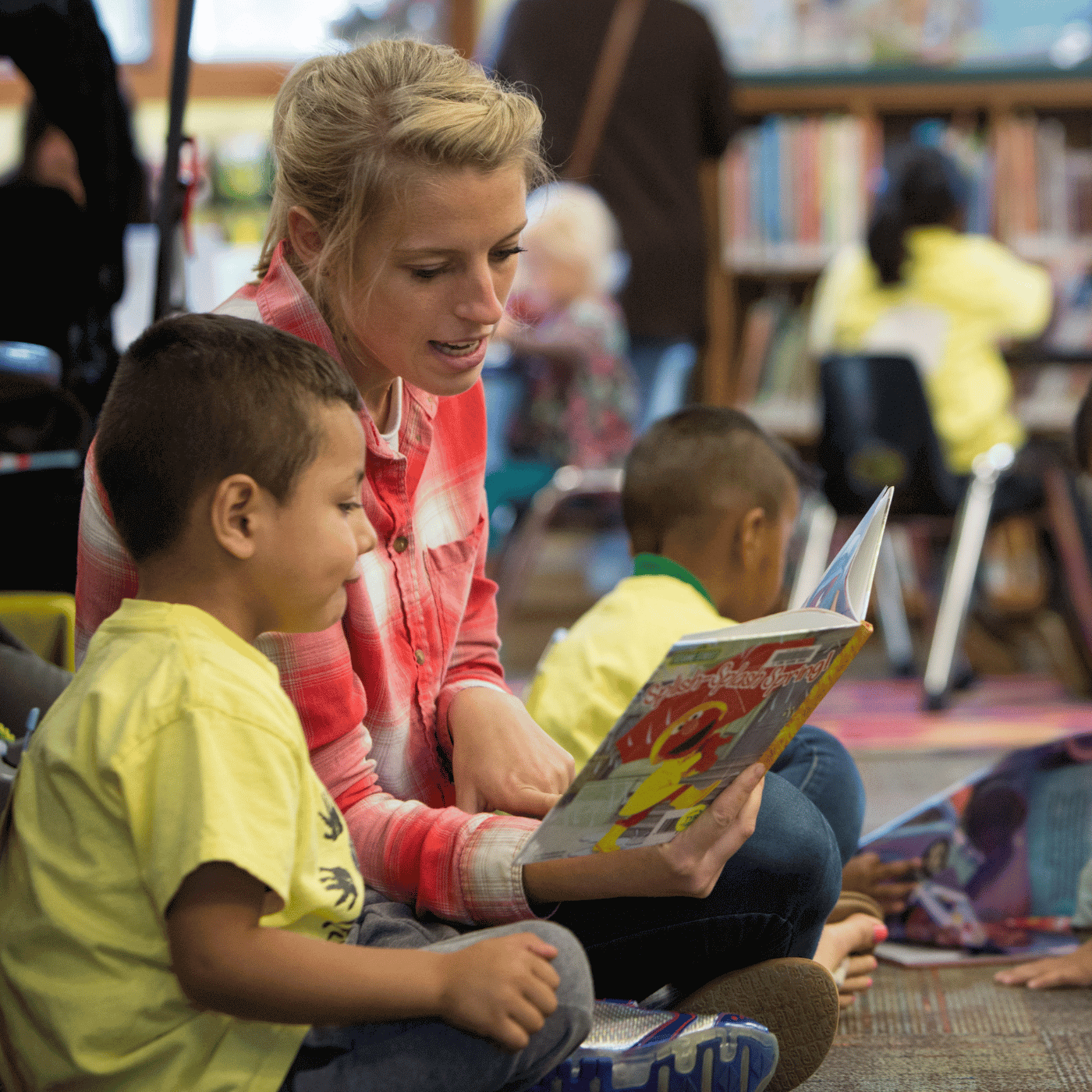 An adult reading to a child in a library room