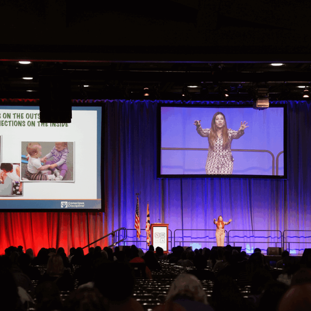 A presenter on a large dramatic stage at NHSA's conference