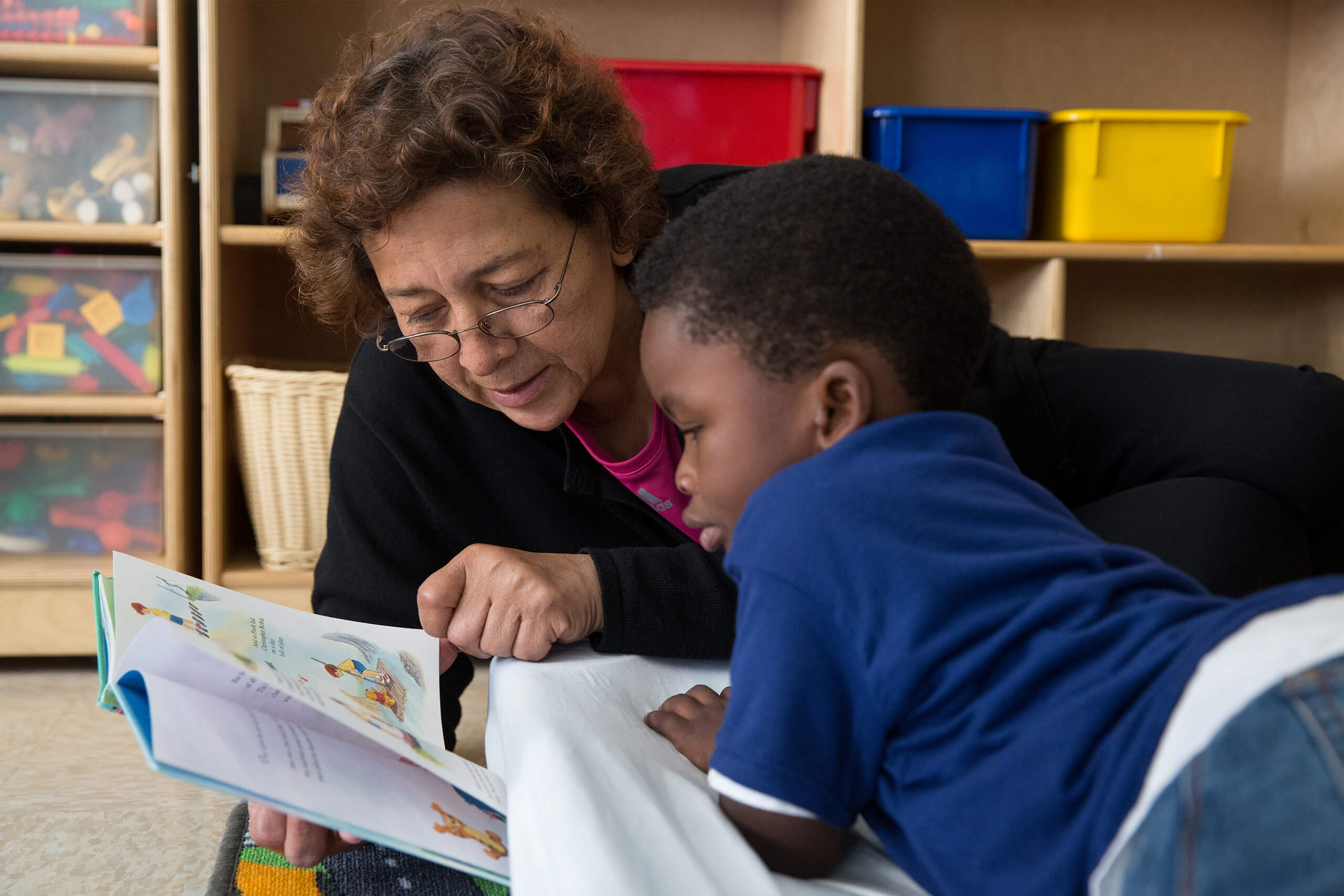 A female teacher reading a book to a young child